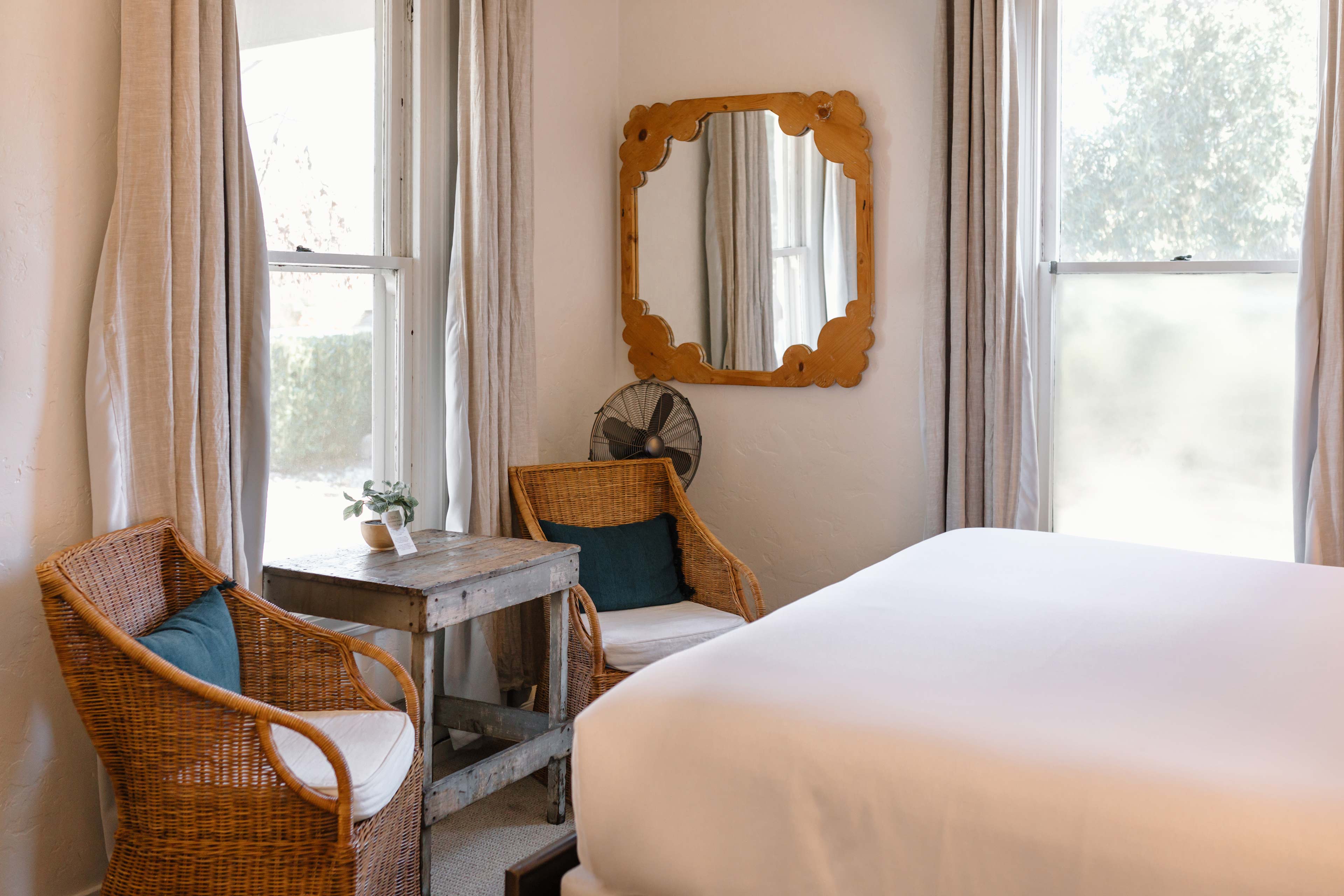 the interior of a room that has wicker chairs and a bed with a white comforter